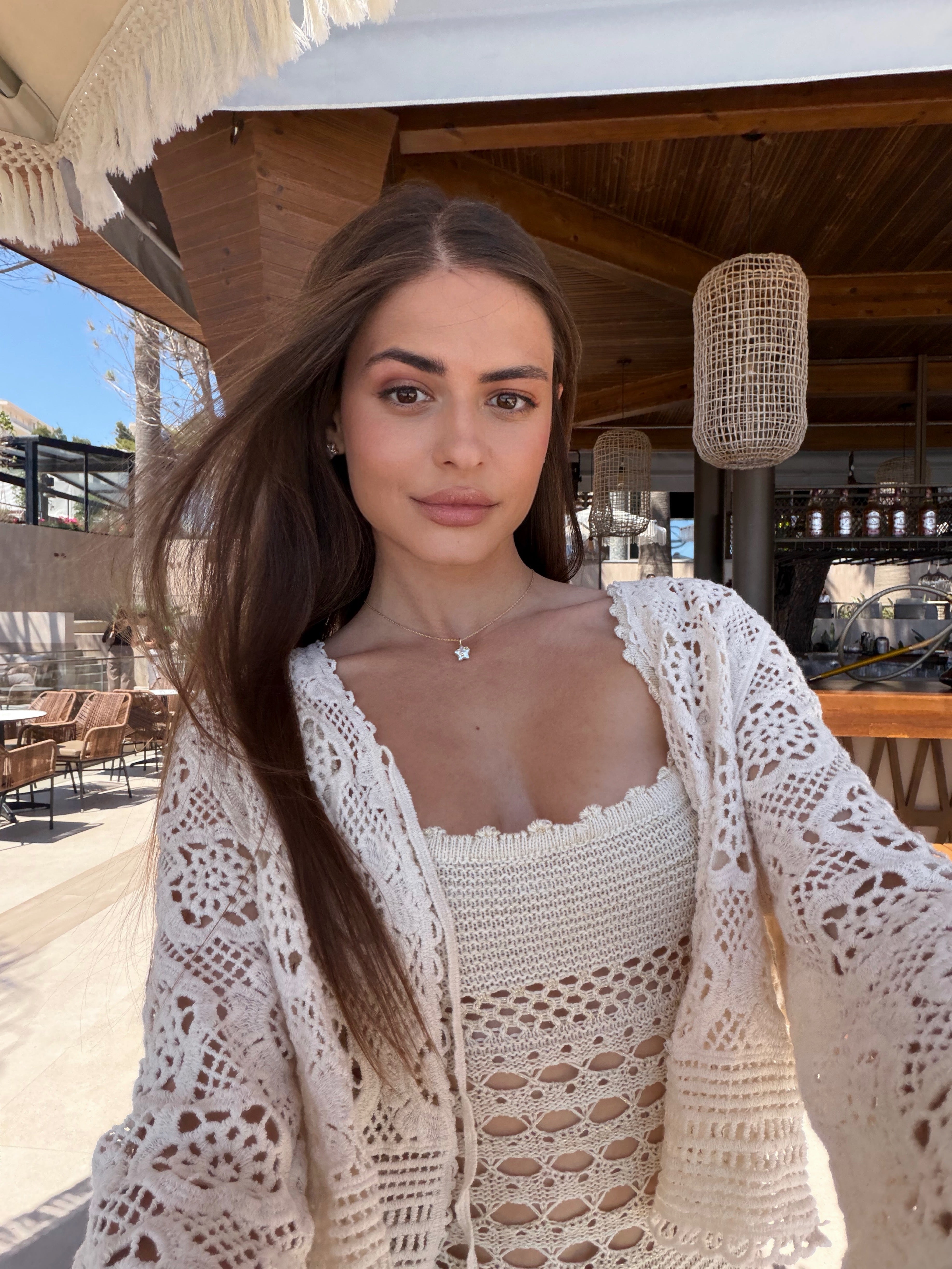 Woman wearing a white crochet cover-up in an outdoor setting