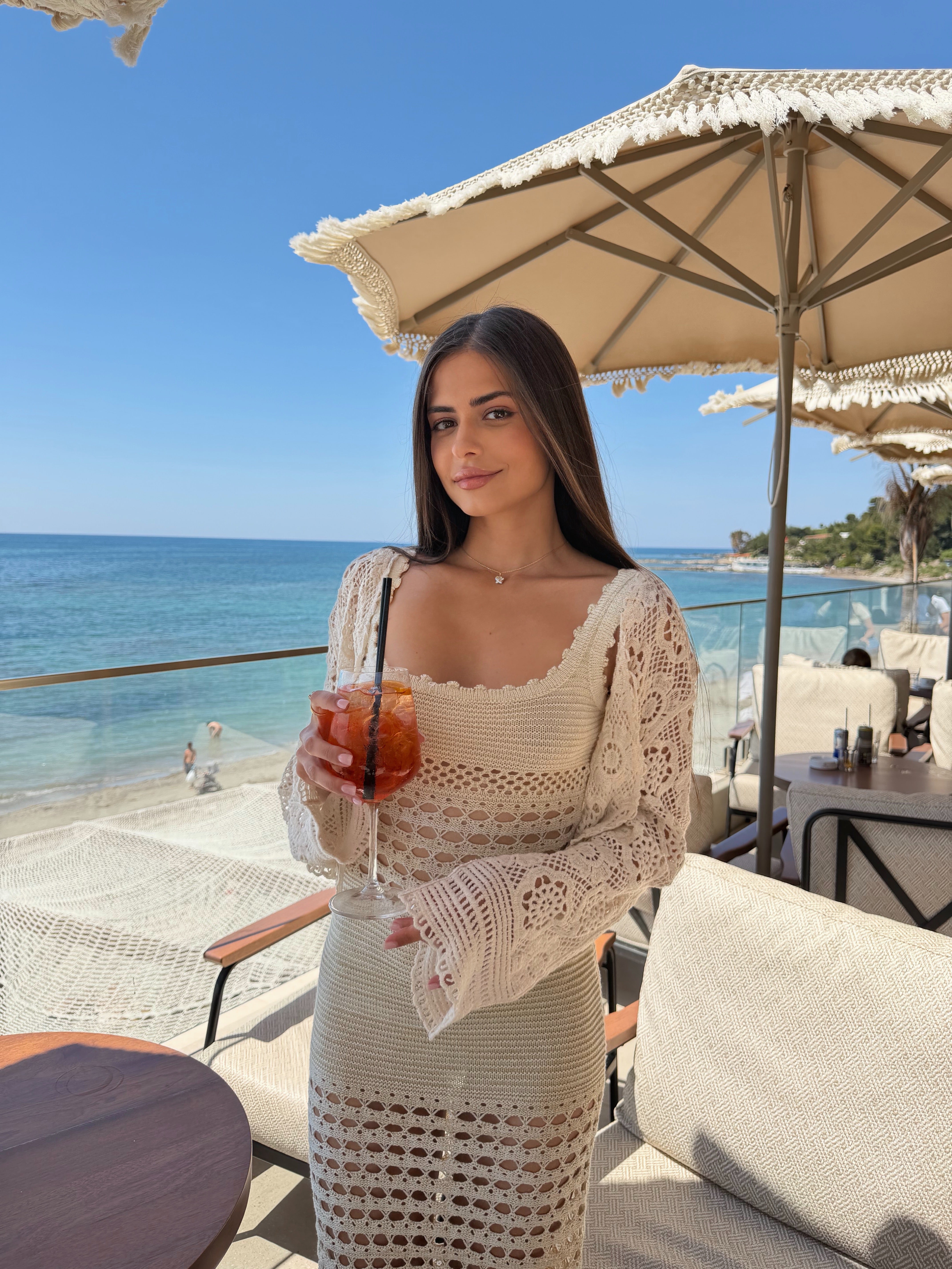 Woman holding a drink by the beach with ocean view